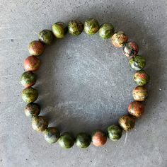 Unakite is a beautiful, grounding stone that helps you connect with the earth. It's said to be especially helpful for those who are constantly on the go, as it provides stability and balance. What could be more perfect than a piece of Unakite Bracelet to keep you connected to the energy of the earth?

This unakite bracelet is the perfect way to bring some positive energy into your life. The unique mix of green and pink crystals is said to promote balance and harmony while helping to enhance your Earthy Green Bracelets For Meditation, Earthy Natural Stones Bracelet For Healing, Healing Jasper Bracelets With Natural Stones, Jasper Bracelets For Healing With Round Beads, Earthy Natural Stones Stretch Bracelet For Healing, Spiritual Jasper Gemstone Beads Bracelets, Spiritual Jasper Bracelets With Gemstone Beads, Healing Jasper Beaded Bracelets With 8mm Beads, Earthy Jasper Round Bead Bracelets