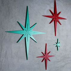 three red and one green paper stars on a white surface