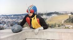 a man in a clown mask sitting on top of a wall next to a ball