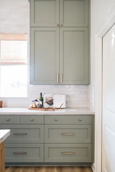 a kitchen with green cabinets and white counter tops