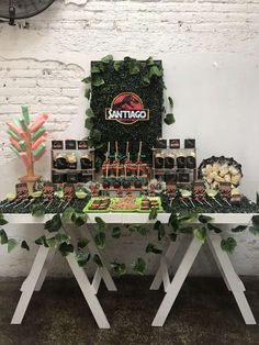 a table topped with lots of desserts and cupcakes next to a wall