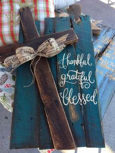 a wooden cross sitting on top of a table next to pillows and other items with words written on it