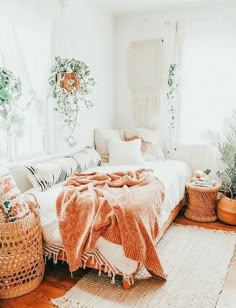 a bed with blankets and pillows on top of it in a room filled with potted plants