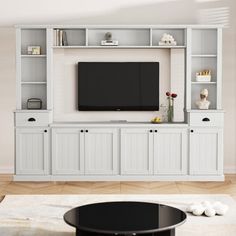 a living room with white furniture and a flat screen tv mounted to the side of it