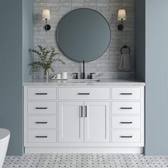 a bathroom vanity with a round mirror above it and two lights on either side of the sink