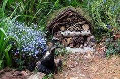 a pile of logs sitting in the middle of a garden filled with flowers and plants