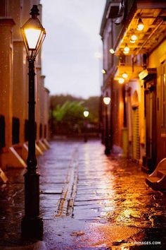 a street lamp on a rainy night in the city with lights shining down from it's windows