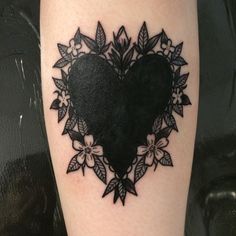 a black heart tattoo with flowers and leaves