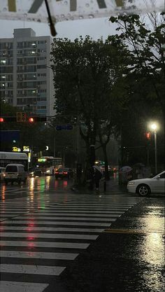 cars are driving down the street in the rain