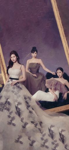 three women in dresses are sitting on a couch and one woman is taking a selfie