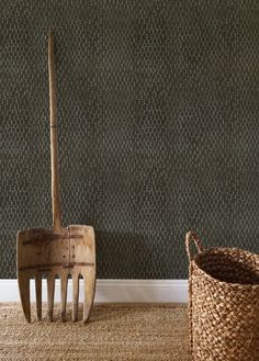 two garden tools sitting on the floor next to a basket and wallpapered wall