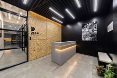 an office lobby with black walls and wood paneling on the wall, along with a reception counter