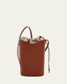 Il Bisonte "Roseto" vegetabletanned Vacchetta leather and cotton bucket bag with iconic wave contour    Flat shoulder strap, 14.2" drop    Drawstring closure     Lining: Cotton    Approx. 9.1"H x 3.9"W x 8.7"D    Item Weight (Lbs.): 1.1    Made in Italy Leather Bucket Bag, Leather Bucket, Cowhide Leather, Bucket Bag, Neiman Marcus, Cotton Canvas, Tops Designs, Shoulder Strap, In Italy