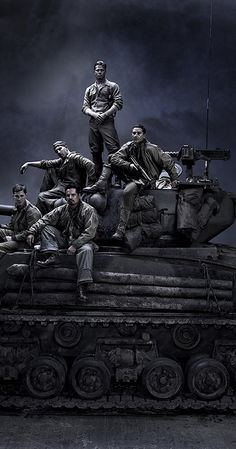 a group of men sitting on top of a tank in front of a dark sky