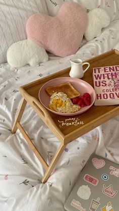 a breakfast tray with toast, fruit and yogurt is on a bed next to a pink heart shaped pillow