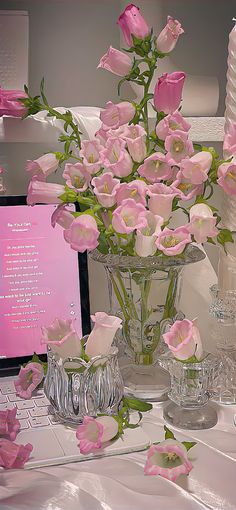 a vase filled with pink flowers sitting on top of a table next to a keyboard