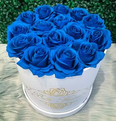 a white box filled with blue roses on top of a table