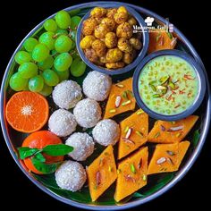 a platter filled with fruits and desserts on top of a table next to other foods