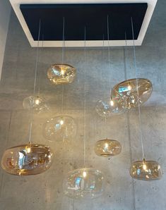 a bunch of lights hanging from the ceiling in a room with concrete flooring and walls