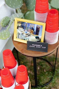 there are many cups on the table with a picture frame and cactus in the background