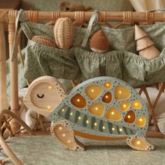 a wooden turtle with lights on its back in front of a crib filled with stuffed animals