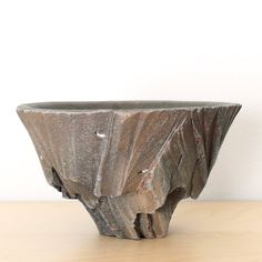 a large gray vase sitting on top of a wooden table next to a white wall