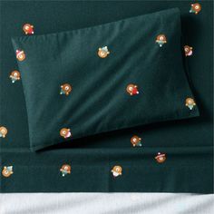 a bed with green sheets and pillow cases covered in cartoon characters on the coverlet