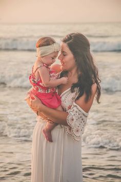 a woman holding a baby on the beach