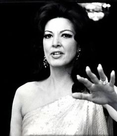 a woman in a white dress holding her hand out to the side with one hand