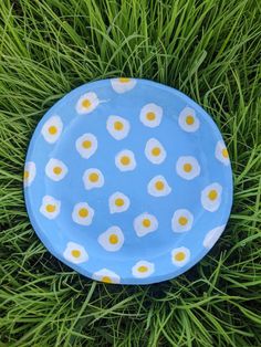 a blue plate with white and yellow eggs on it sitting in the grass, top view