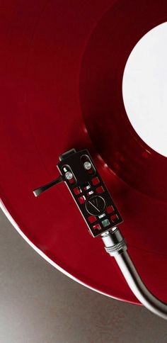 a red record player sitting on top of a white table next to a black and silver object