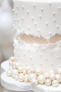 a three tiered white wedding cake with pearls