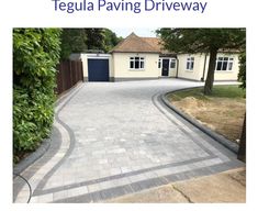 an empty driveway in front of a house with trees and bushes on the side walk