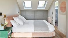 a bedroom with a bed, nightstands and two windows in the ceiling above it