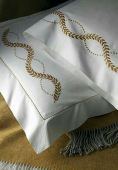 two white pillows with gold trim on them