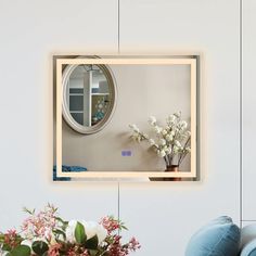 a mirror that is on the wall above a vase with flowers in front of it