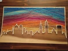 a string art city skyline is displayed on a wooden table with strings attached to it