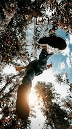 a man riding a skateboard up the side of a tree covered forest under a blue sky