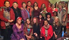 a group of women standing next to each other in front of a red curtain on a stage