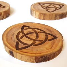 three wooden coasters with designs on them sitting on a white surface, one has a knot in the middle