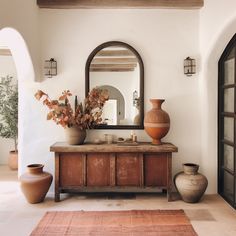 a room with a mirror, vases and other items on the table in front of it