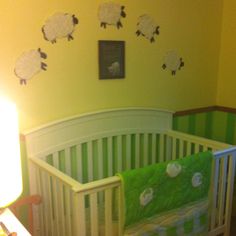 a baby crib with sheep decals on the wall next to it's bed