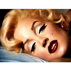 a woman laying on top of a bed with her eyes closed and lashes curled up