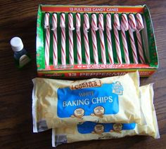 candy canes and baking chips in a box on a wooden table next to each other