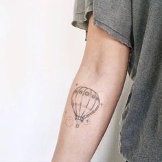 a man with a tattoo on his arm holding a hot air balloon in the sky