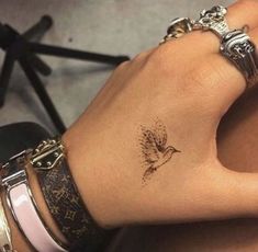 a woman's wrist with a small bird tattoo on the left side of her arm