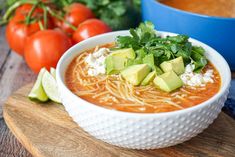 a white bowl filled with soup and topped with avocado