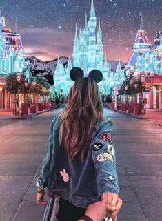 a woman walking down a street with mickey mouse ears on her head and the castle in the background