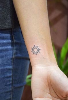 a woman's arm with a small sun tattoo on her left wrist and an arrow in the middle