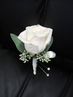 a boutonniere with white flowers and greenery on the back of a car